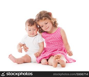 Two lovely sisters sitting on the floor and smiling isolated on white. Two sisters