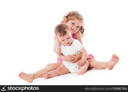 Two lovely sisters sitting on the floor and smiling isolated on white. Two sisters