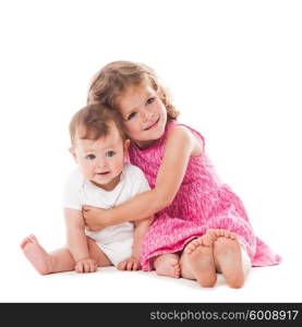 Two lovely sisters sitting on the floor and smiling isolated on white. Two sisters isolated