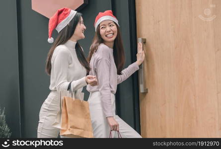 Two lovely women holding bags while doing window shopping at department store in Christmas season. New Year Celebration and Sales Discount Concept.