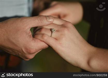 two lovers, a couple, a boy and a girl are holding hands. The girl on her hand is a wedding ring. dark background the view is close. the concept of love. two lovers, a couple, a boy and a girl are holding hands. The girl on her hand is a wedding ring. the concept of love