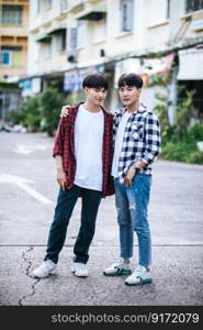 Two loving young men in shirts and standing on the street.