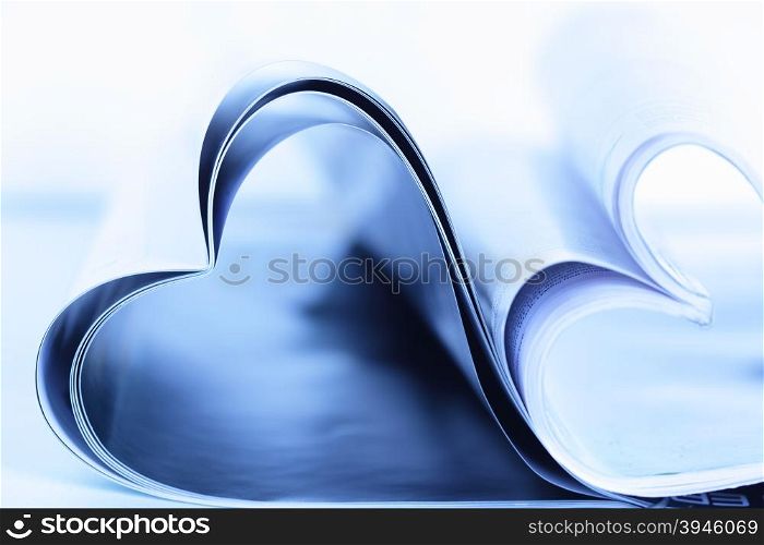 Two magazines folded to heart shape on table