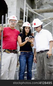 Two male and a female architects standing at a construction site