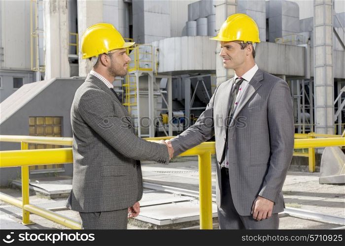 Two male architects shaking hands at construction site