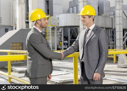 Two male architects shaking hands at construction site