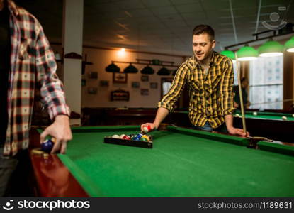 Two male billiard players places colorful balls, poolroom. Men plays american pool game in sport club. Two male billiard players places colorful balls