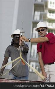 Two male construction workers working at a construction site
