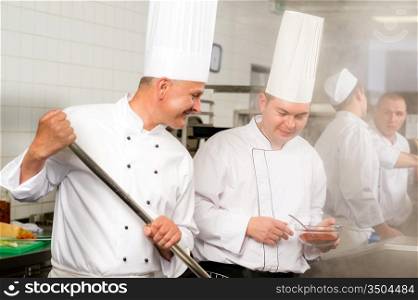 Two male cooks working in professional industrial kitchen prepare food