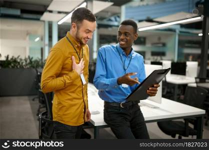 Two male employees, meeting in IT office. Professional teamwork and planning, group brainstorming, modern company interior on background. Two male employees, meeting in IT office