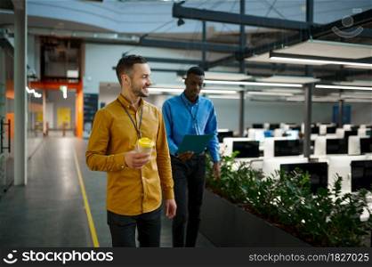 Two male employees, meeting in IT office. Professional teamwork and planning, group brainstorming, modern company interior on background. Two male employees, meeting in IT office
