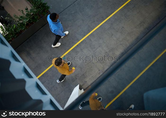Two male employees, top view from balcony in IT office. Professional teamwork and planning, group brainstorming, modern company interior on background. Two employees, top view from balcony in IT office