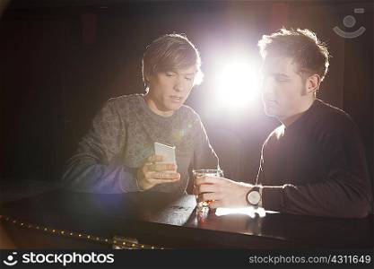 Two male friends looking at smartphone in nightclub