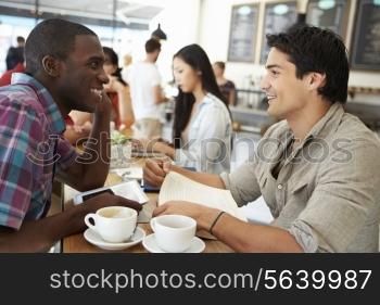 Two Male Friends Meeting In Busy Coffee Shop