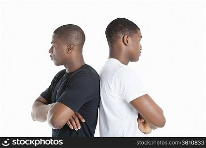 Two male friends standing back to back over gray background