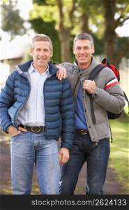 Two Male Friends Walking Outdoors In Autumn Park Together