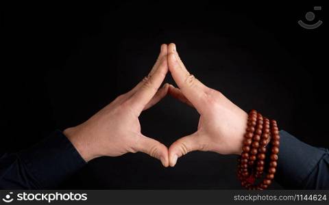 two male hands connected on a black background, demonstration of mudra soaring lotus
