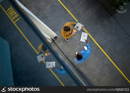 Two male managers are talking in IT office, top view. Professional teamwork and planning, group brainstorming, modern company interior on background. Two managers are talking in IT office, top view