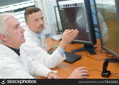 two male medical staff consulting computer screens