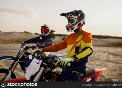 Two male moto biker in protective helmet on iron horse portrait. Motocross extreme sport challenge. Male moto bikers in protective helmet portrait