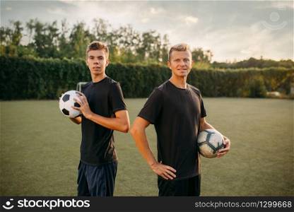 Two male soccer players holding balls in hands on the field. Footballer on outdoor stadium, workout before game, football training