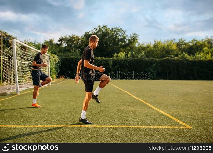 Two male soccer players training on the field. Footballers on outdoor stadium, team workout before game