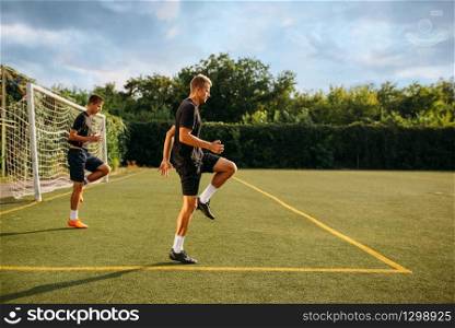 Two male soccer players training on the field. Footballers on outdoor stadium, team workout before game