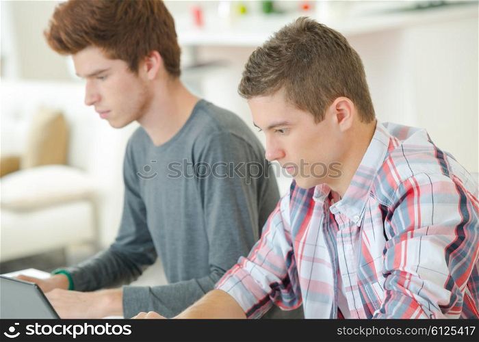 Two male students using laptops