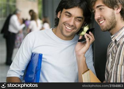 Two male university students listening to a mobile phone