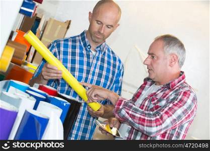 two male workers choosing roll of palstic film