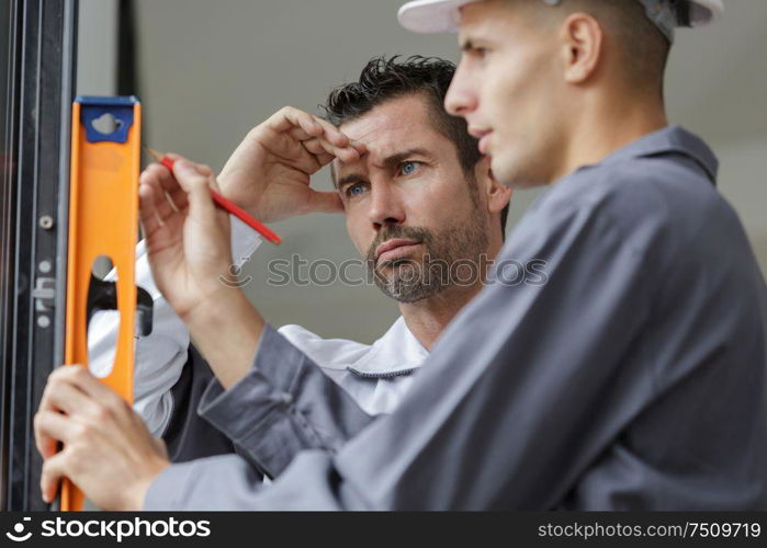 two man wall holding spirit level