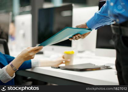 Two managers exchange documents in IT office. Professional teamwork and planning, group brainstorming, modern company interior on background. Two managers exchange documents in IT office