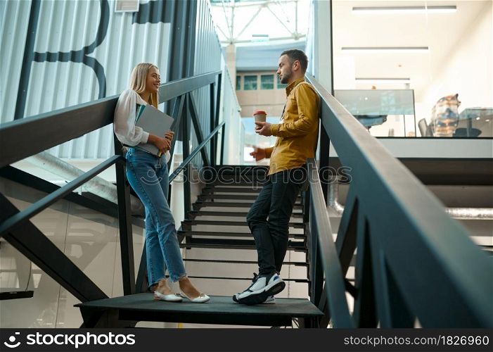 Two managers talks on stairs in IT office. Professional teamwork and planning, group brainstorming and corporate work, modern company interior on background. Two managers talks on stairs in IT office