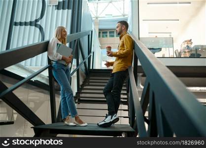 Two managers talks on stairs in IT office. Professional teamwork and planning, group brainstorming and corporate work, modern company interior on background. Two managers talks on stairs in IT office