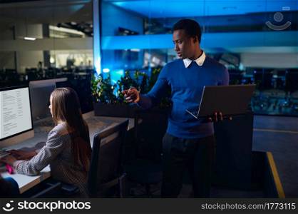 Two managers works in night office. Smiling male and female workers, dark business center interior on background, modern workplace. Two managers works in night office