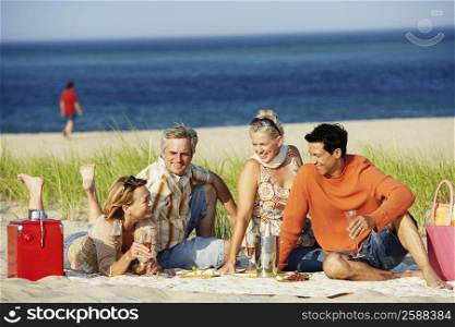 Two mature couples sitting on the beach