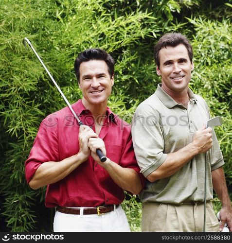 Two mature men holding golf clubs and smiling