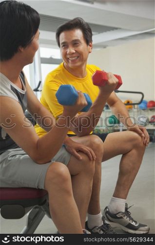 Two mature men lifting weights in the gym