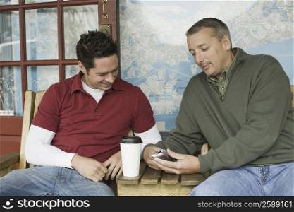 Two mature men looking at a mobile phone