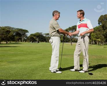 Two mature men shaking hands on golf course