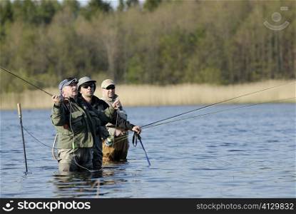 Two mature men with a mid adult man fishing in the river