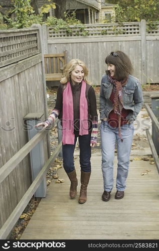 Two mature women crossing a bridge