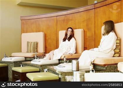 Two mature women getting pedicure in a beauty parlor