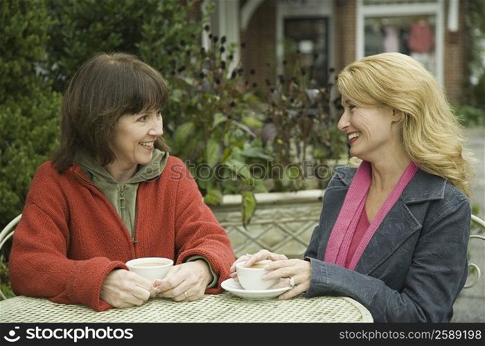 Two mature women having tea and smiling