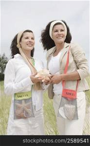 Two mature women holding a conch shell and smiling
