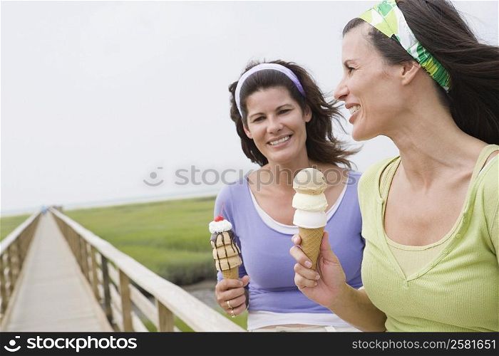 Two mature women holding ice cream cones and smiling