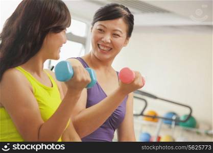 Two mature women lifting weights in the gym