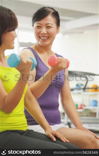 Two mature women lifting weights in the gym