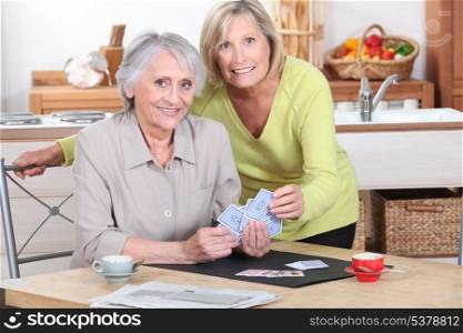 Two mature women playing cards.