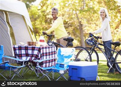 Two Mature Women Riding Bikes On Camping Holiday